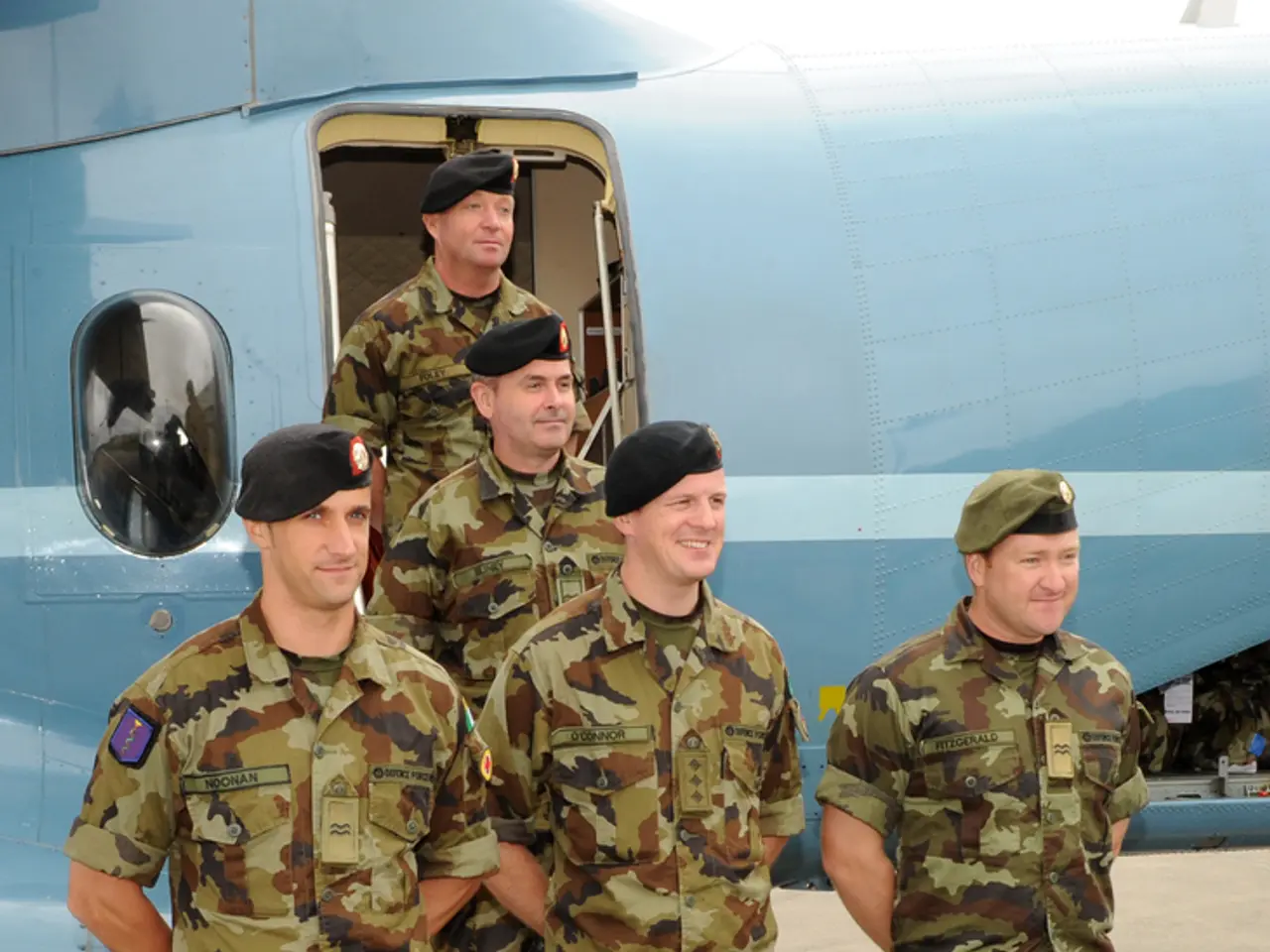 This picture describes about group of people, they wore caps, behind them we can see a plane.