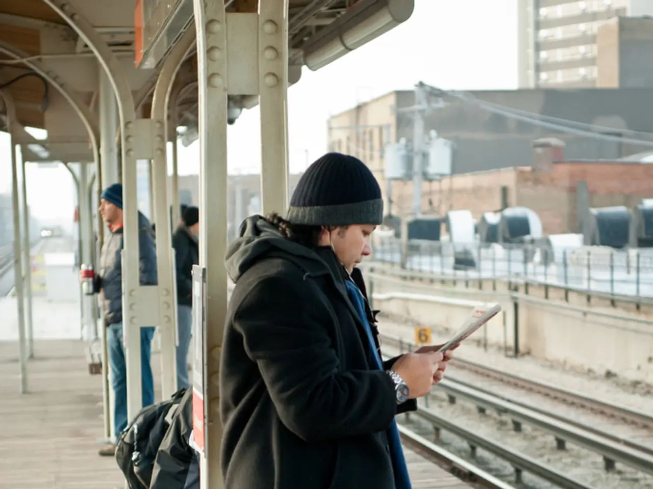 In this picture we can see the man in the front, wearing black jacket and standing on the railway...