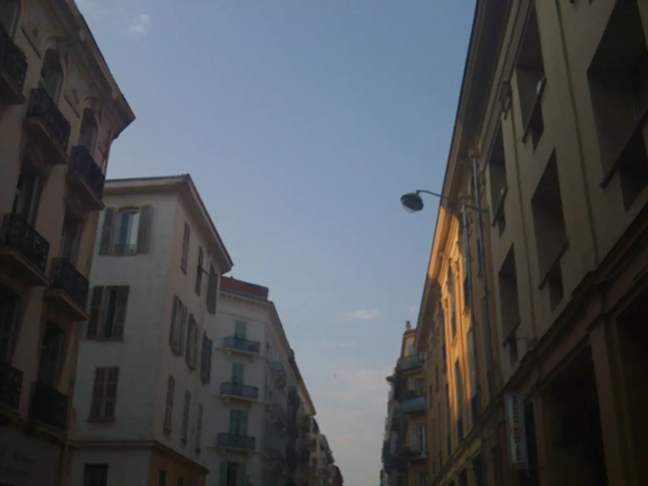 In this picture we can see few buildings, light and clouds, in the bottom right hand corner we can...