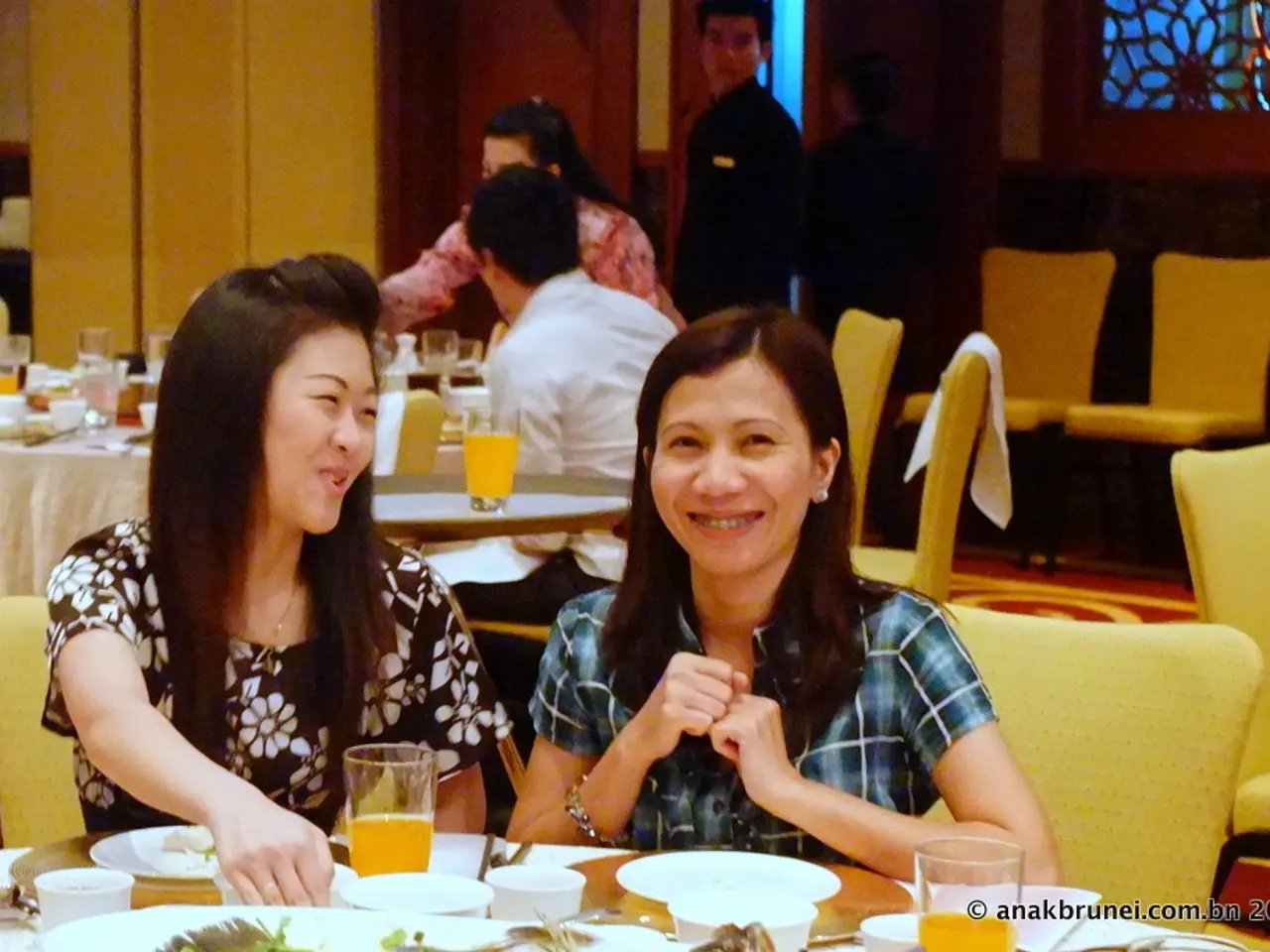 In this image I can see number of people are sitting on chairs. Here on this table I can see few...