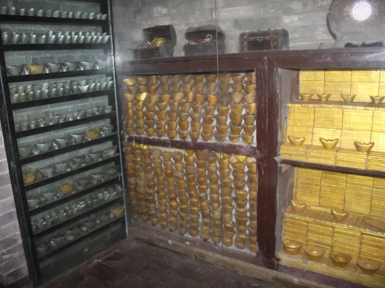 The image shows a room filled with lots of different types of gold bars arranged in racks, with a...