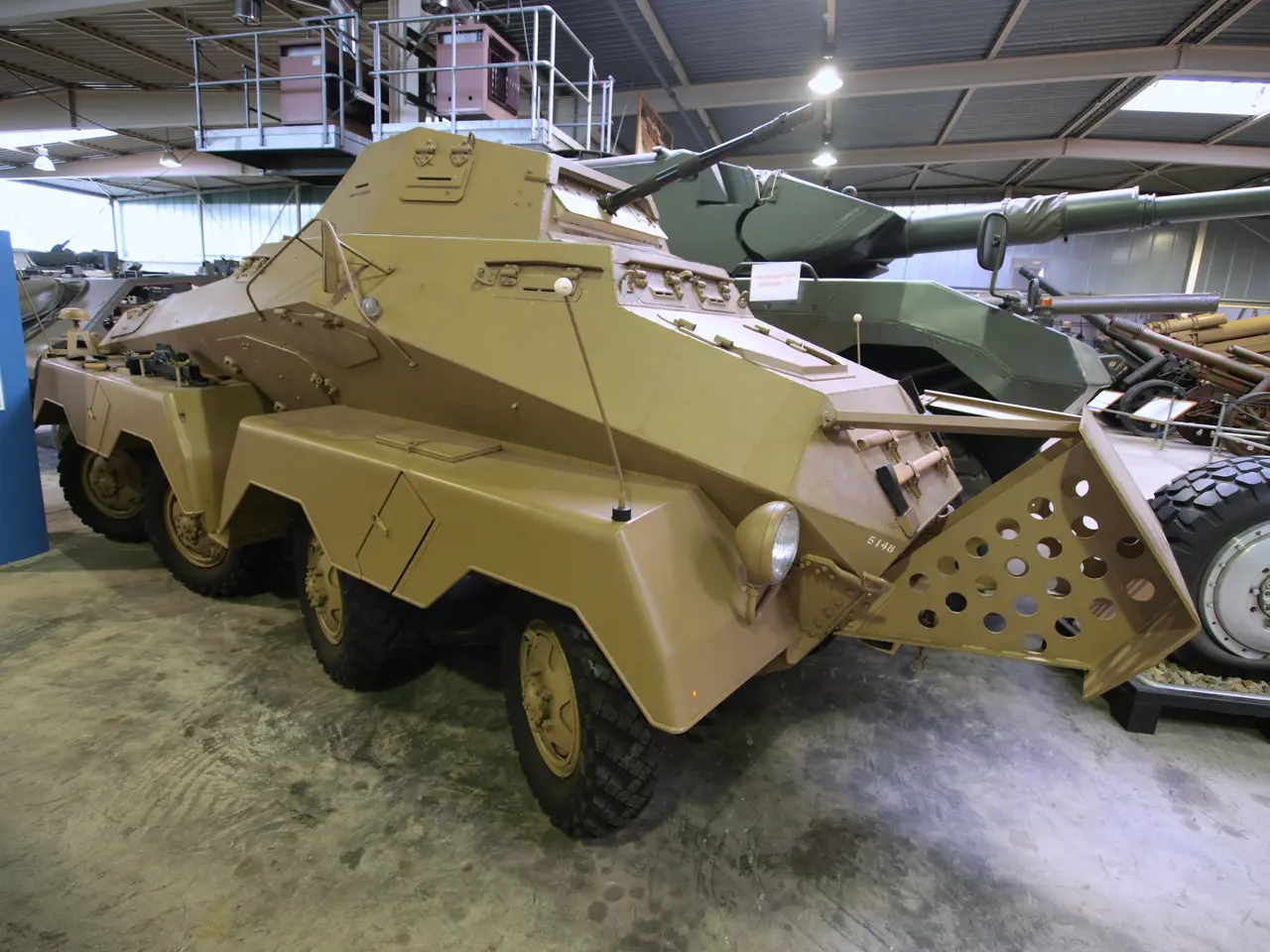 The image shows an armored personnel carrier parked inside of a building, surrounded by other...