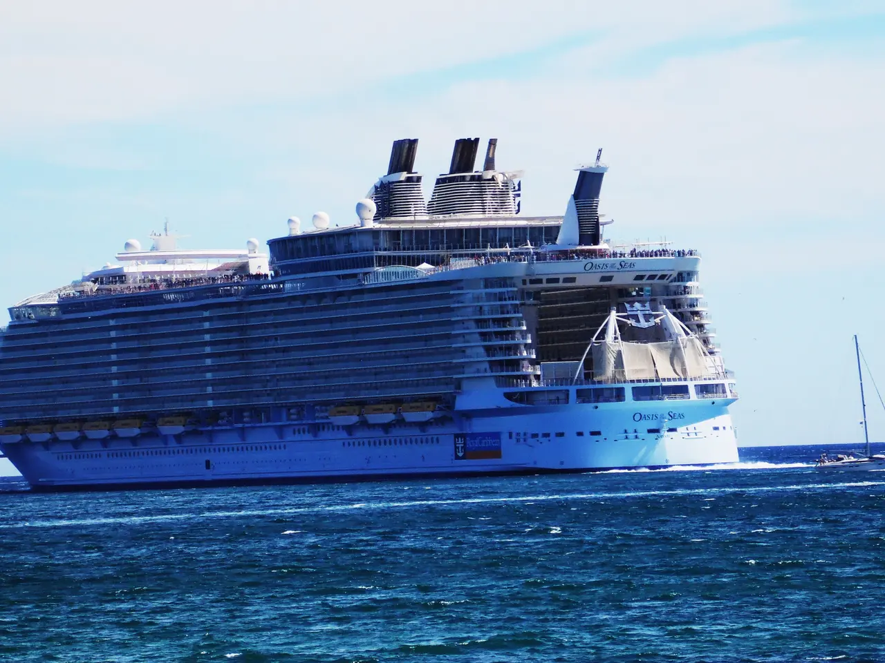 The image shows Royal Caribbean's Oasis of the Seas, a large cruise ship, sailing on the water with...