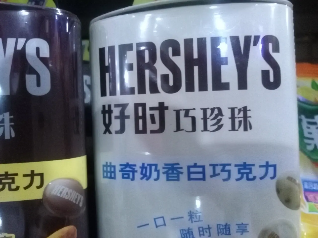 The image shows two cans of Hershey's sitting side by side on a shelf. The cans are white with...
