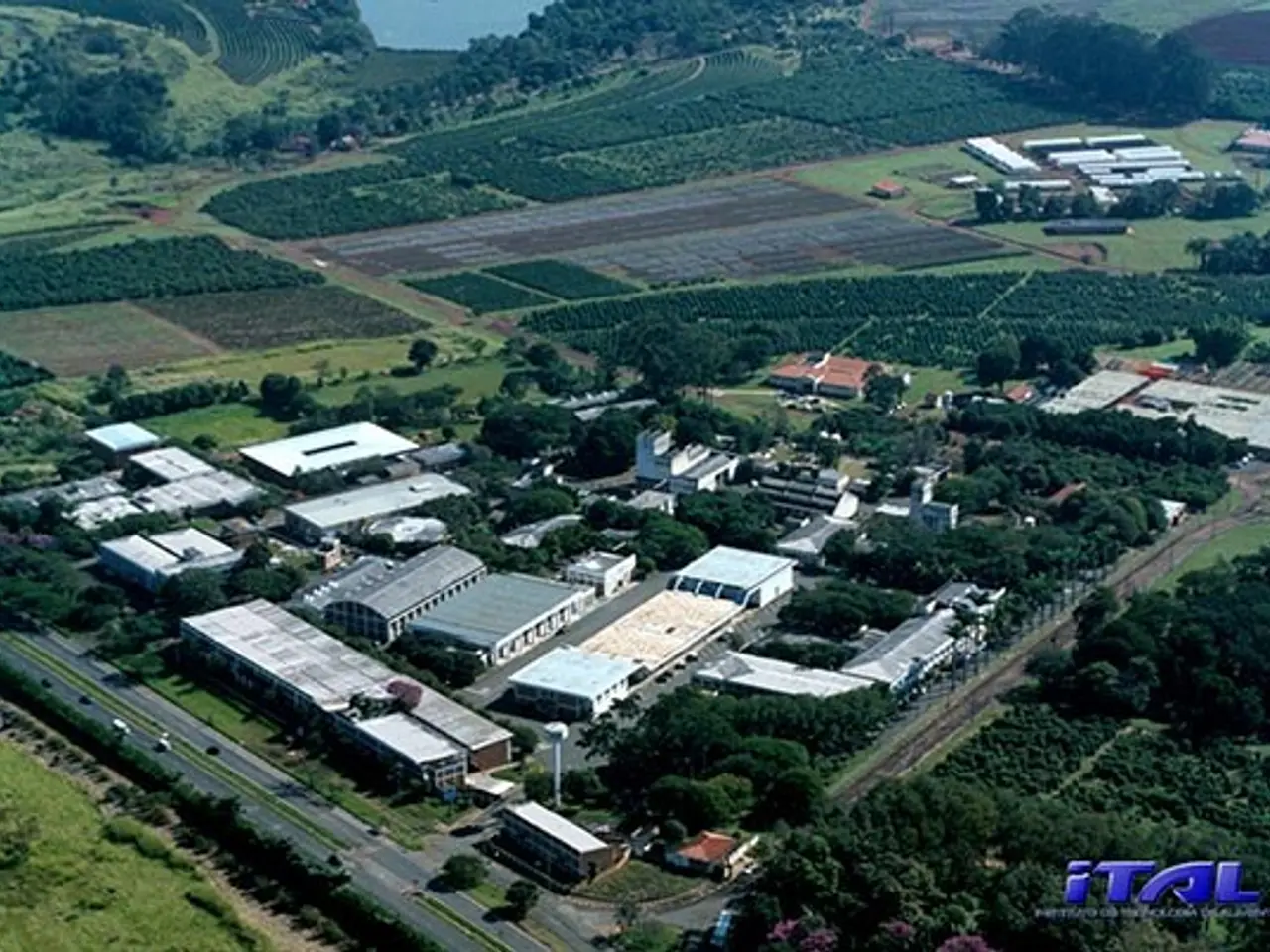 The image shows an aerial view of a large industrial area in the middle of a field, surrounded by...