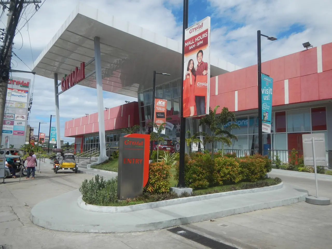 The image shows a gas station with a lot of cars parked in front of it, surrounded by buildings,...