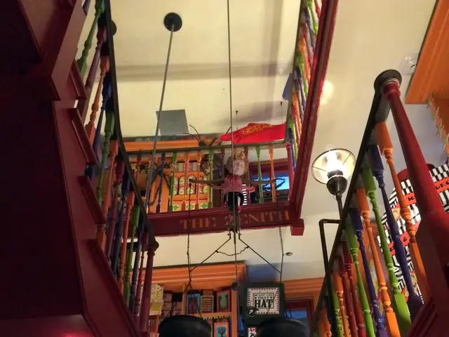 In this image we ca see a building with stairs, fence, lamps, a doll, a sign board and a roof.