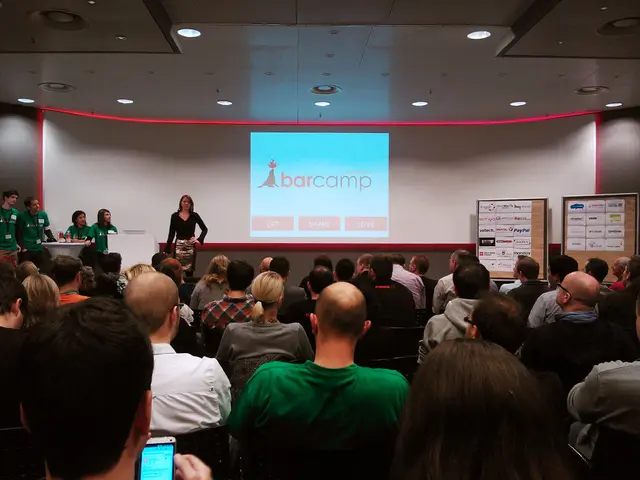 In this image we can see a group of people are sitting on the chair. There is a projector screen...