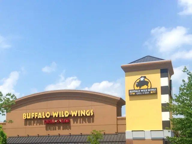 In this image we can see one building looks like a hotel, some text on the building, three boards...