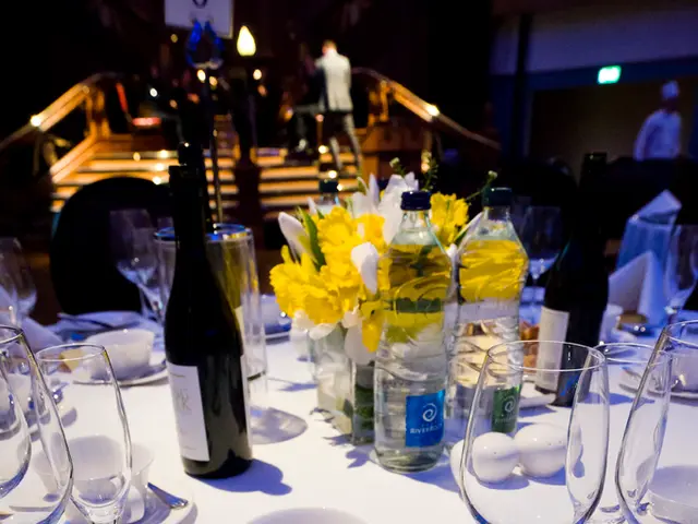 In this image there is a table in which there are glass, cup, saucer, name paper, menu card or...