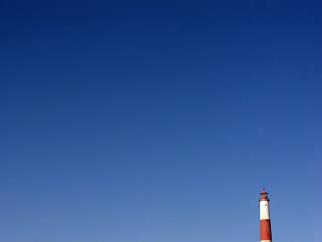 In this image, we can see a building and there is a tower. At the bottom, there is ground.