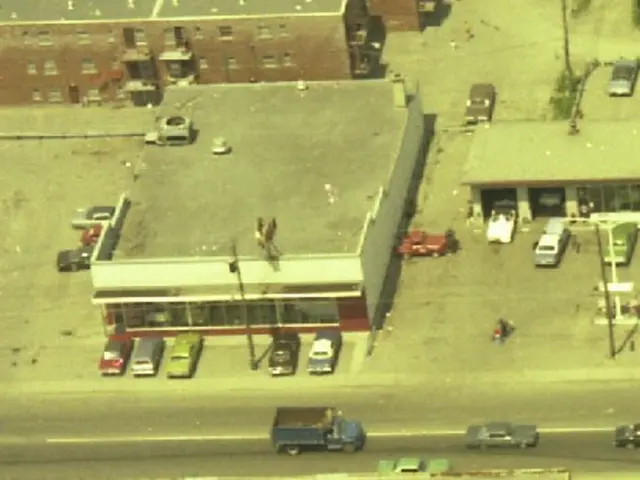 This is the aerial view image of a town, there are many cars all around the buildings and some cars...