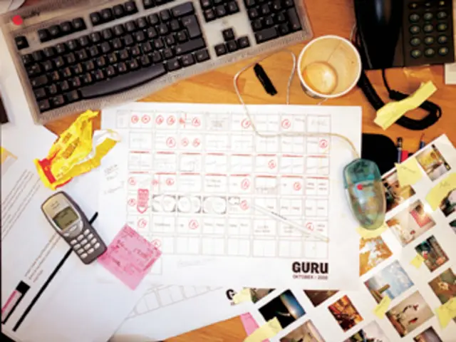 This picture shows papers,computer, telephone, cups mobile phone on the table