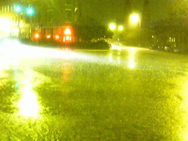 The picture is captured while raining and there is a road and there is a building at the center of...