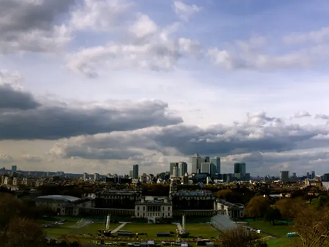 In this image we can see there is a beautiful view of buildings, trees and clouds in the sky.
