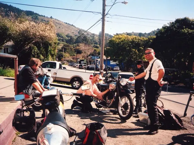 in this picture we see few men with the motor cycles and few cars parked along and we see some...