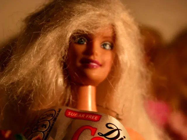 In this image we can see a doll wearing a sugar free diet coke tag.