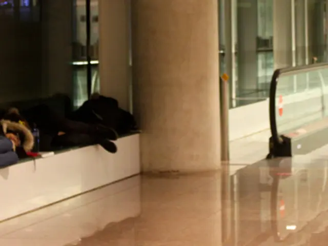 The picture is clicked in a airport where we observe few people are sitting on the bench and we...