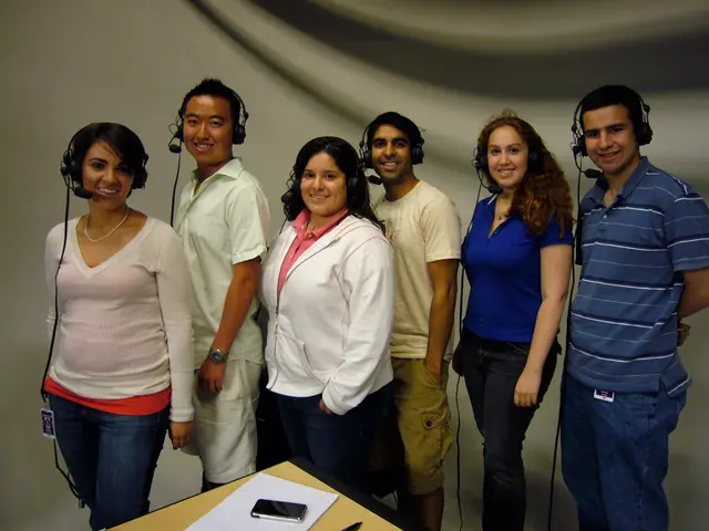 In this picture we can see six people wore headsets, standing, smiling and in front of them we can...