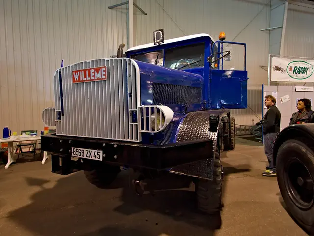 In this image there is a truck in the middle. On the right side there are few people standing...