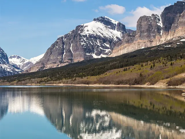 The image shows a stunning view of Glacier National Park in Montana, with a lake in the foreground...