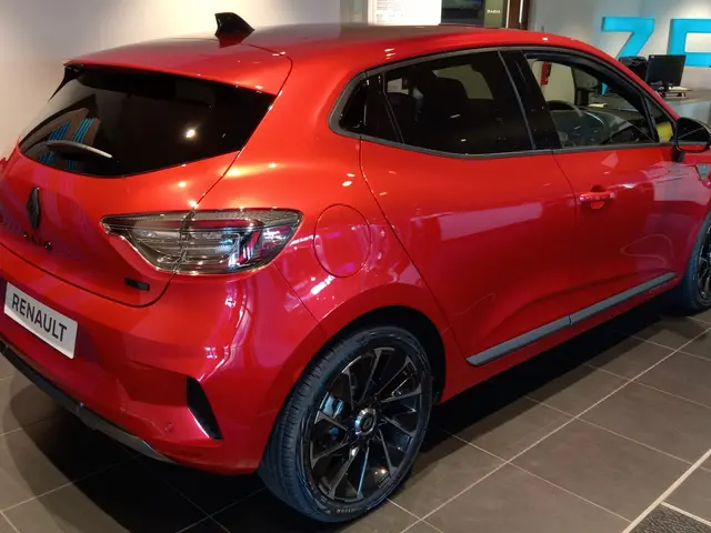 The image shows a red Renault Clio RS Trophy R parked in a showroom, surrounded by black bedroom...