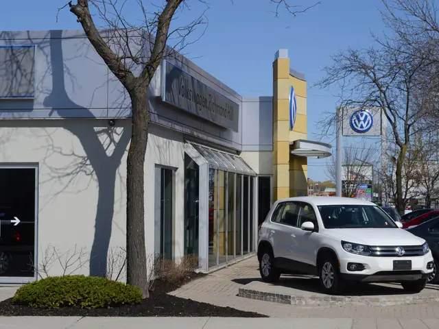 The image shows a white Volkswagen dealership with cars parked in front of it, surrounded by trees,...