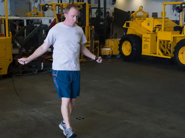 The image shows a man in a white shirt and blue shorts walking through a warehouse, surrounded by...