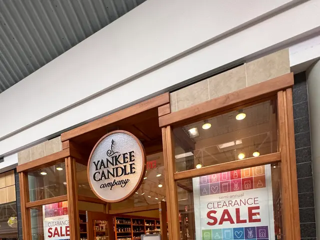 The image shows a store front with a sign that reads "Yankee Candle Clearance Sale" and glass walls...