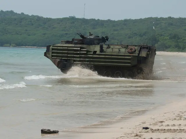 The image shows an amphibious vehicle driving through the water on a beach, with sand visible at...