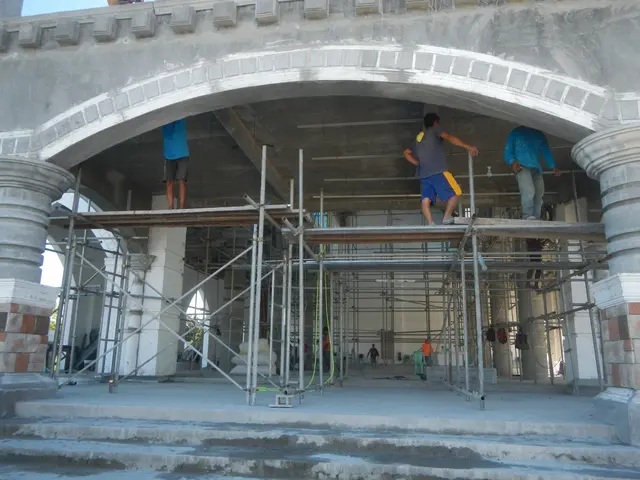 The image shows a group of men standing on top of a building under construction, with scaffolding...