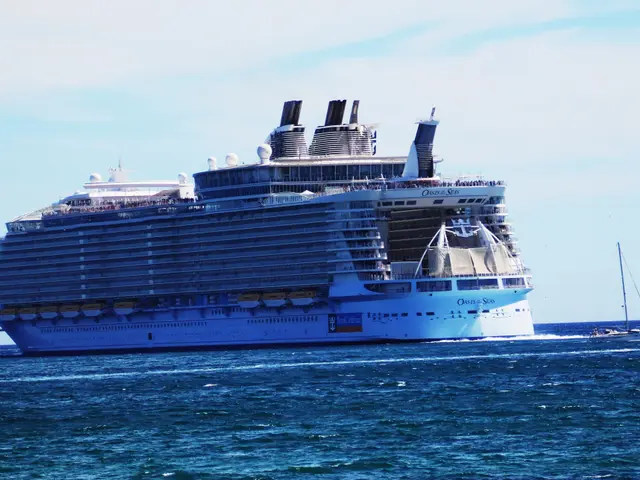 The image shows Royal Caribbean's Oasis of the Seas, a large cruise ship, sailing on the water with...
