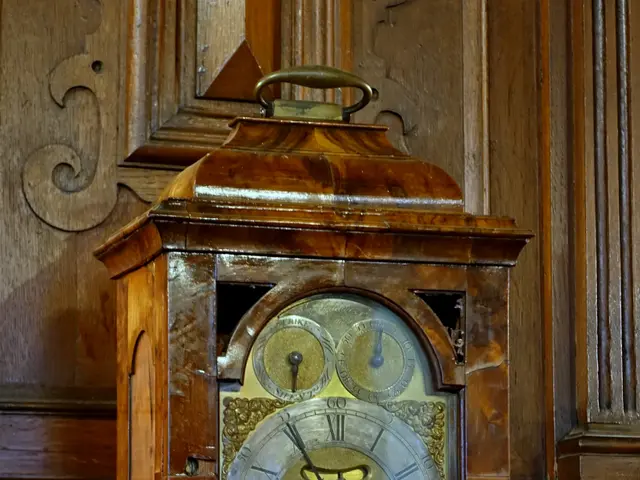 The image shows an old wooden clock sitting atop a marble counter, with a wooden wall in the...