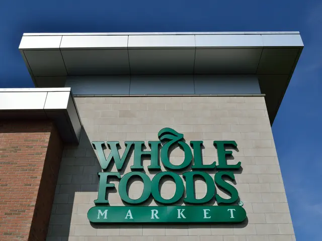 The image shows a Whole Foods Market sign on the side of a building, with a bright blue sky in the...