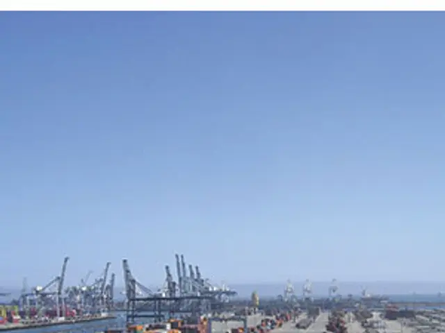 The image shows a large container ship docked at the port of Los Angeles, surrounded by vehicles on...
