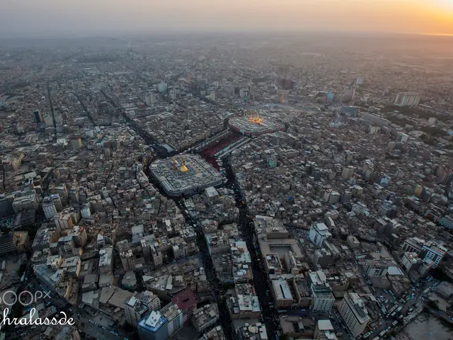 The image shows an aerial view of the city of Tehran at sunset, with many buildings, roads, and...