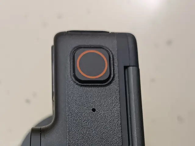 The image shows a close up of a black camera on a white surface. It is a Dji Mavic 2 Pro, a device...