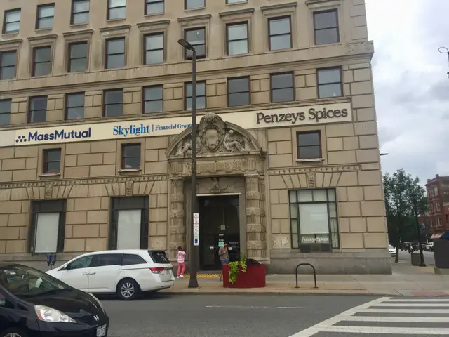 The image shows a large building with cars parked in front of it, surrounded by street poles,...