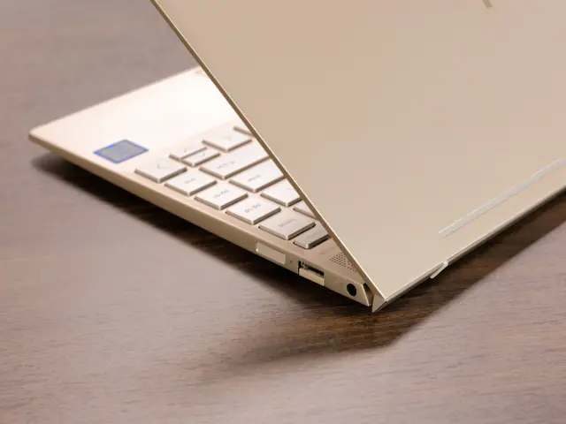 The image shows a laptop computer, a Microsoft Surface Laptop 3, sitting on top of a wooden table....