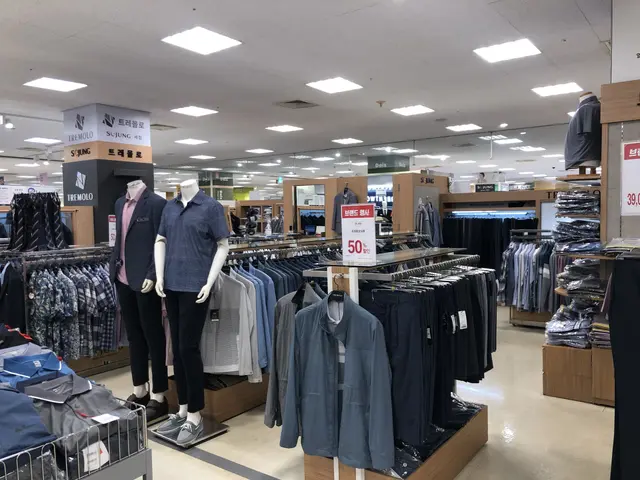 The image shows a clothing store with mannequins in the middle of it, surrounded by racks of...