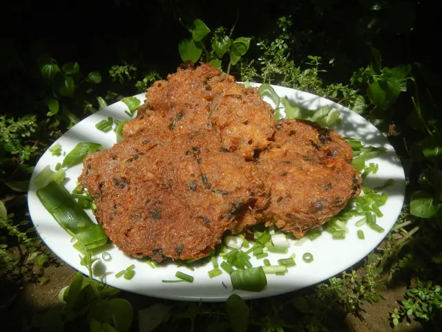 The image shows a white plate topped with two meat patties covered in a savory sauce and garnished...