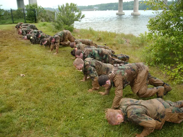 The image shows a group of marines doing push ups on the grass near a body of water, surrounded by...