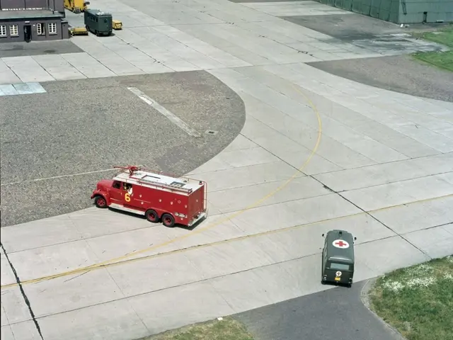 The image shows an aerial view of a red fire truck parked on the tarmac at an airport, surrounded...