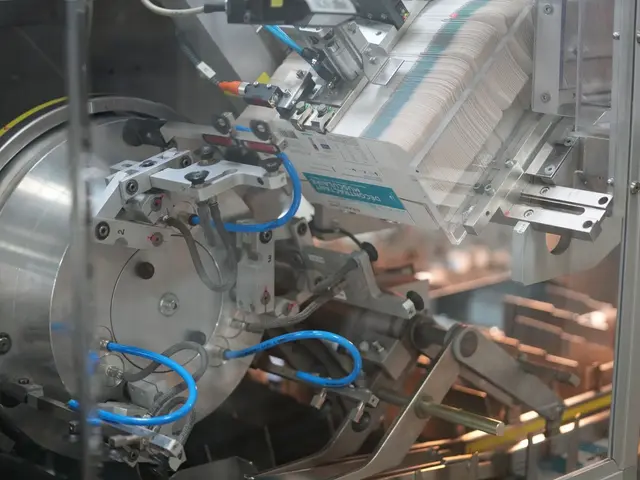 The image shows a machine sitting on top of a table in a factory, with a few objects in the...