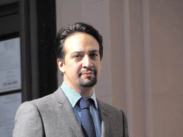 The image shows a man in a suit and tie standing outside of a building, with a wall and a door in...