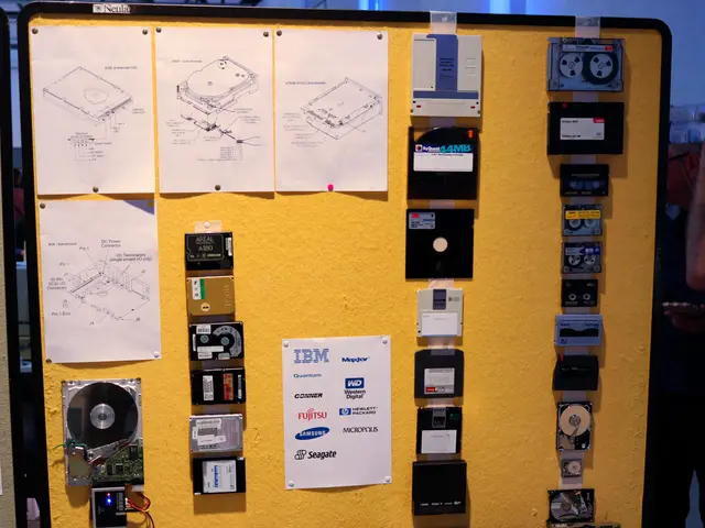 The image shows a table topped with lots of different types of hard drives, with a person standing...