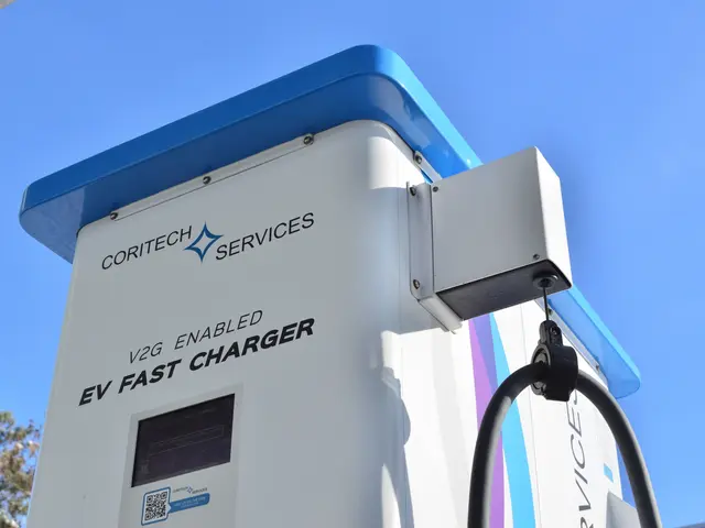 The image shows an electric vehicle charging station with a blue and white sign that reads "V2G...