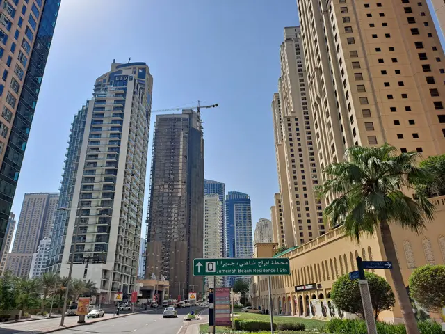 The image shows a bustling city street in Dubai, United Arab Emirates, with tall buildings in the...