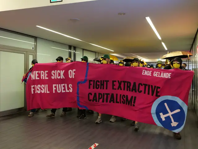 The image shows a group of people wearing masks and holding a banner that reads "We're Sick of...