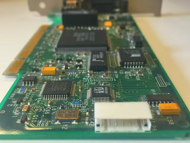 The image shows a close up of a computer motherboard on a table, with a chip in the foreground and...